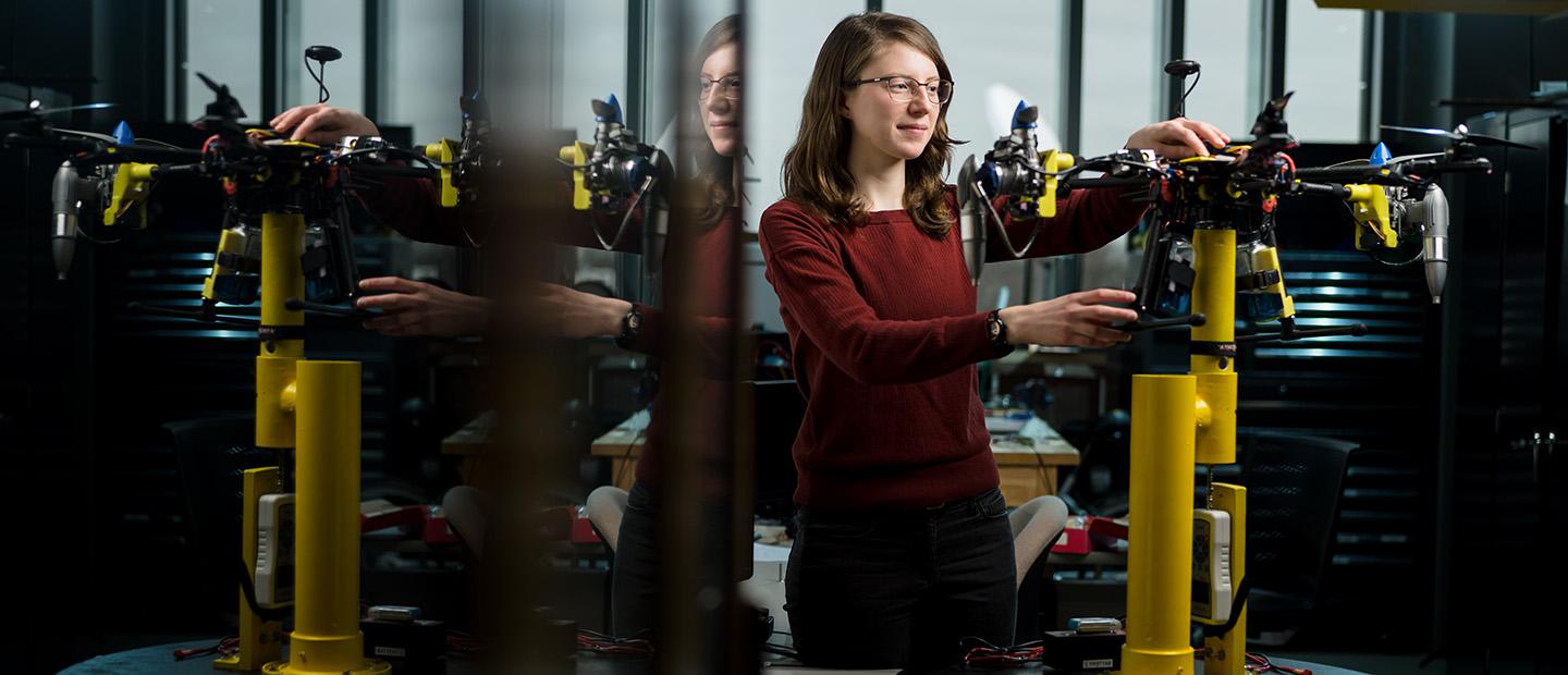 A young woman working with a mechanical device in a lab.